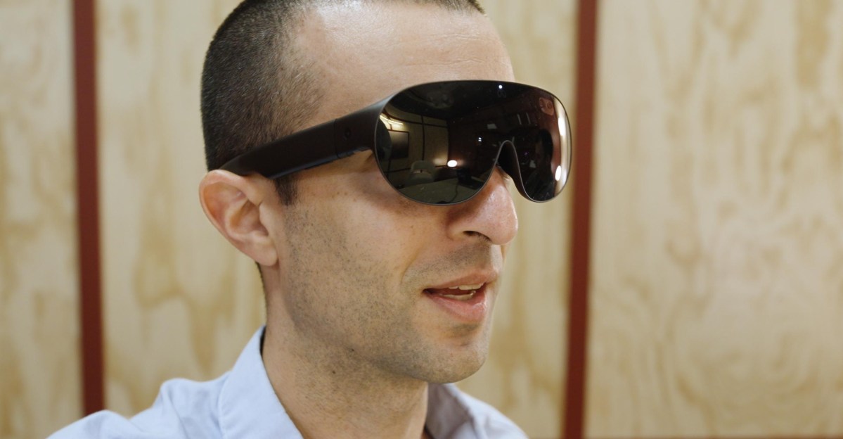 Meta VR Glasses: hefty black sunglasses with blacked-out lenses and immersive displays, shown with the pocket compute puck.